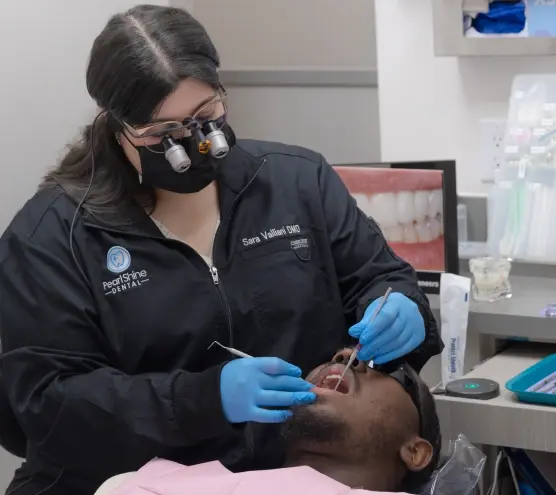 Female dentist performing emergency dental treatment on male patient in Houston office.
