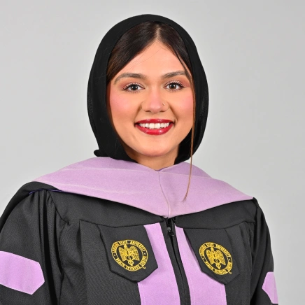 Dr. Ayesha Tabassum smiling in a professional graduation gown portrait