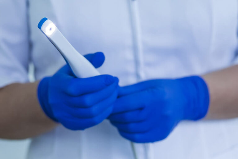 hygienist holding a intraoral camera with blue latex gloves on