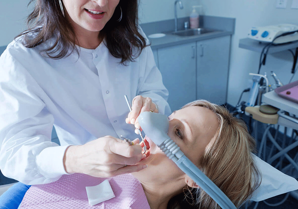 doctor checking a patient's teeth while she receives sedation