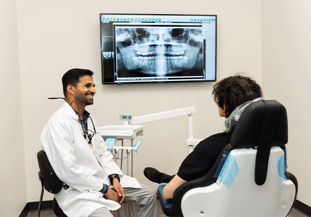 Dr. Charolia smiling while talking to a patient with an x-ray in the background