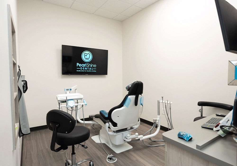 A patient room with a TV, chair, tools, desk, computer, and dental equipment