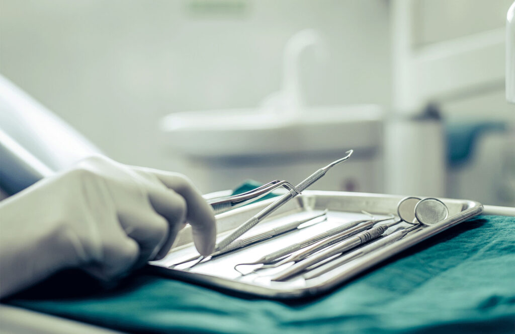 dentist grabbing dental tools that are on a tray